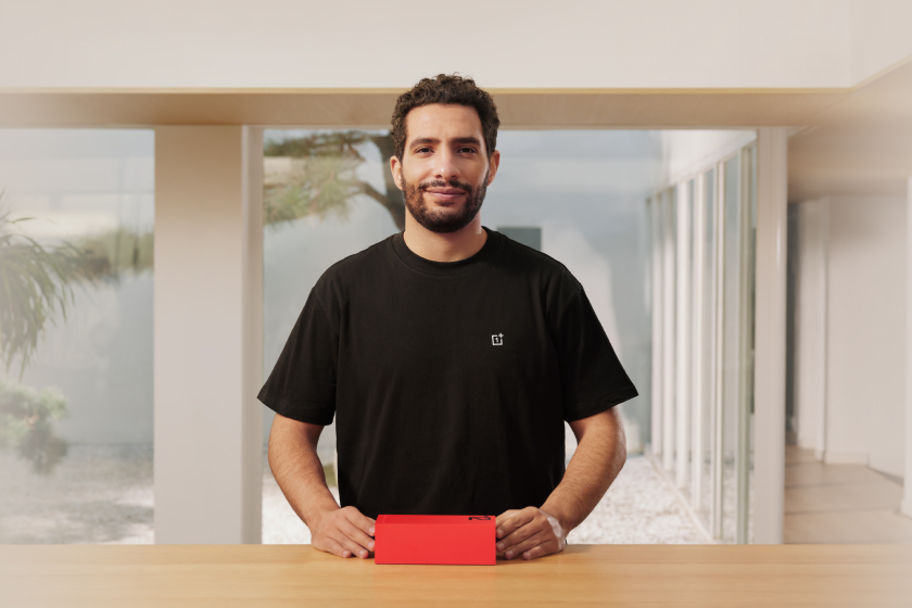 Smiling man in black shirt holding red object.