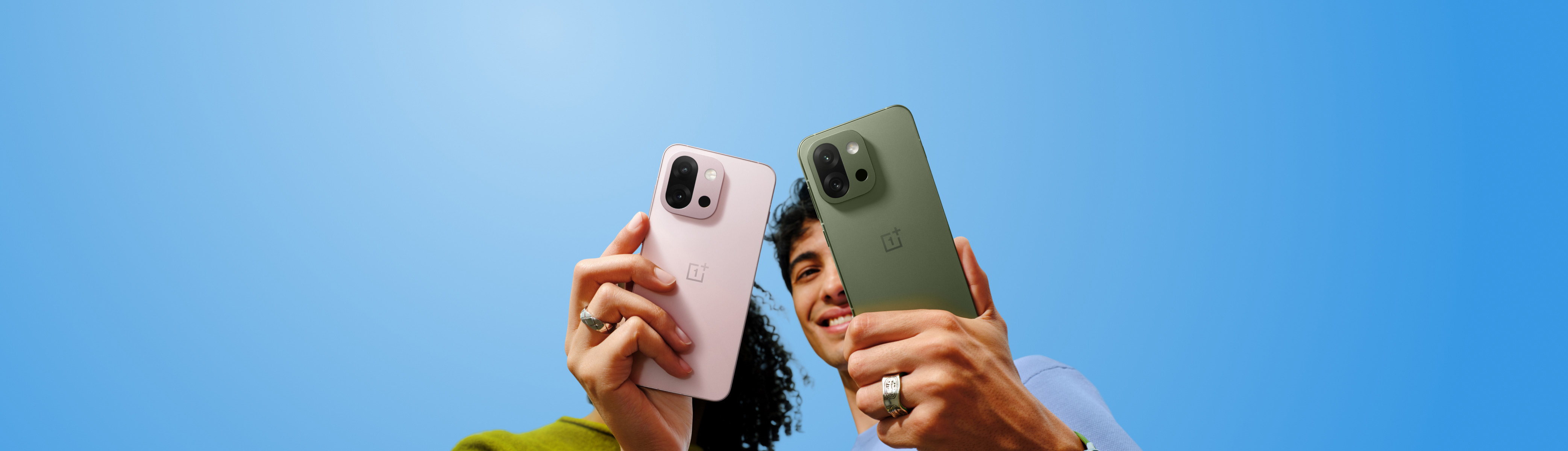 Three sleek, colored OnePlus smartphones in matte black, green, and pink.