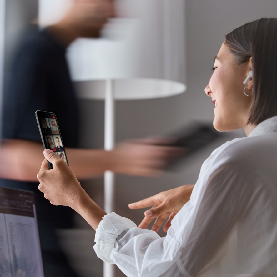 Woman using a smartphone for a video call in a well-lit home.