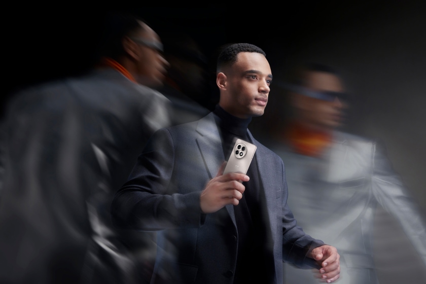 A man in a dark suit holding a smartphone.