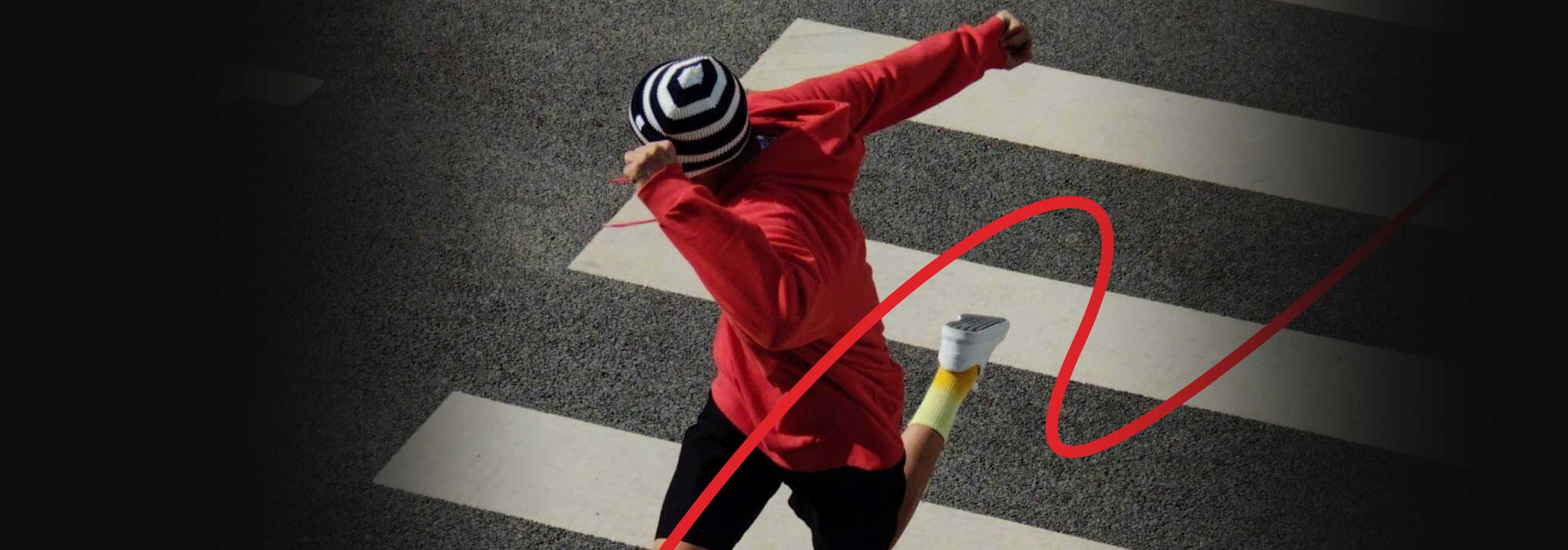 A person in a red jacket and striped hat performing a dance move on a checkered floor.