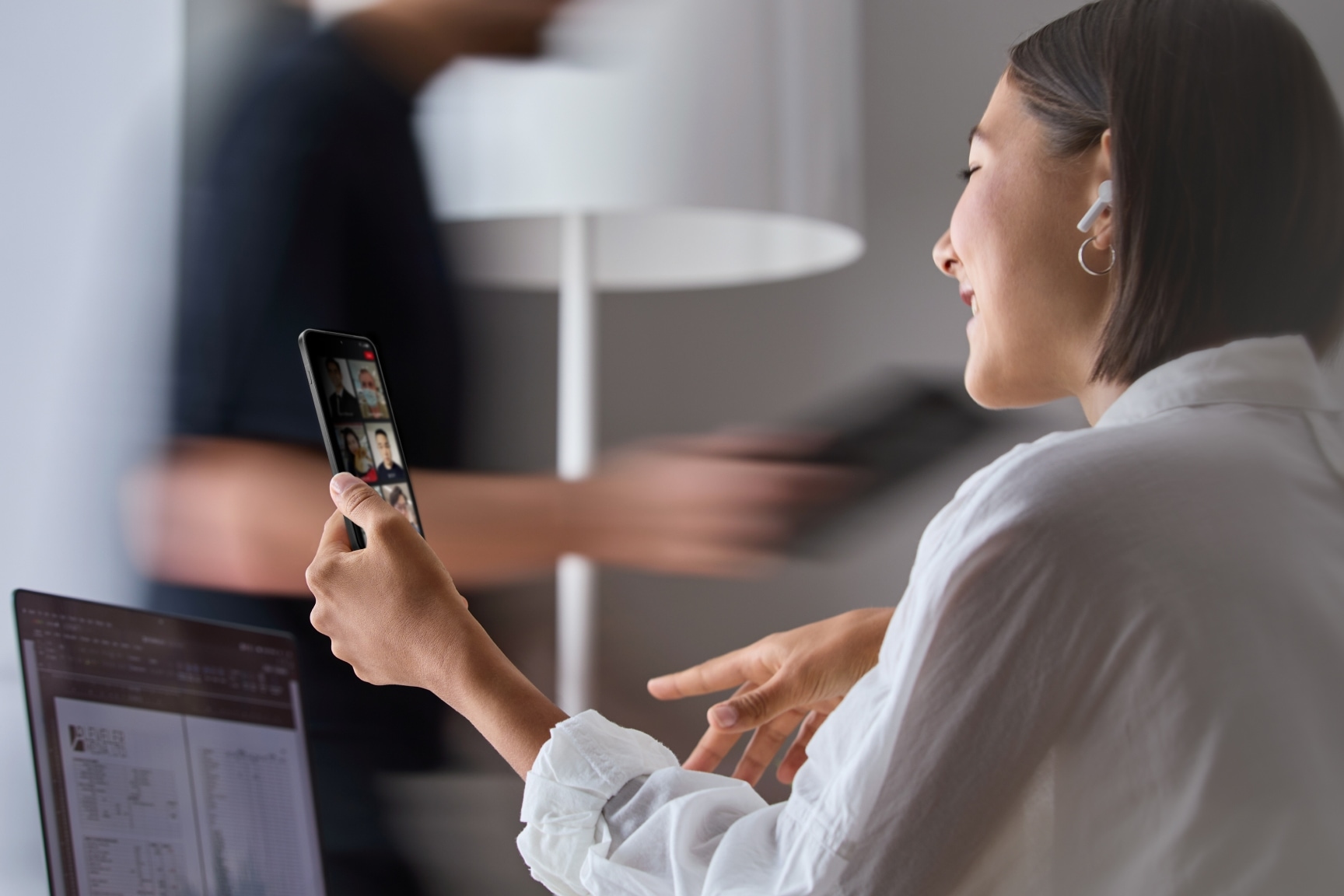 Young woman attending video conference on laptop and phone.